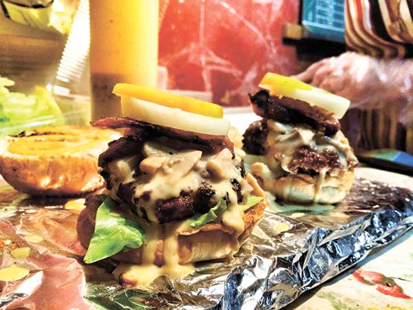 Burgaholic’s famous and super delicious mushroom cheese sauce dripping from the sides of the patties!